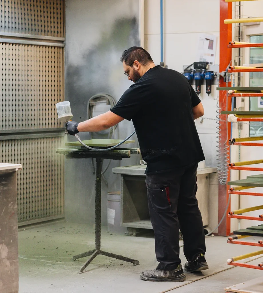 Application de la couleur au pistolet dans l'atelier Morel, utilisant des finitions hydro sans solvants.