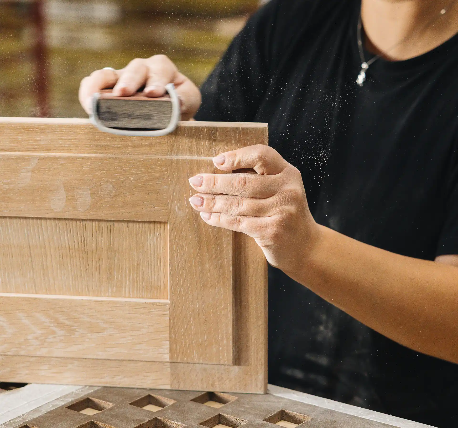 Artisane préparant une façade de meuble en bois dans l'usine de Cuisines Morel en Bretagne.