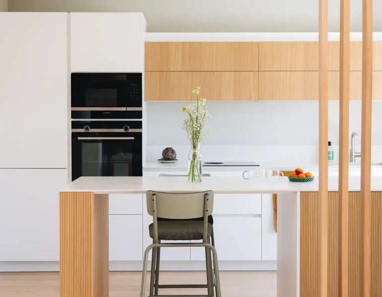 Cuisine Morel avec îlot central en chêne rainuré modèle Sève et façades Fenix Blanc ultra-mattes.