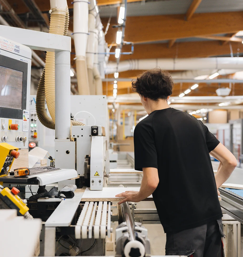 Artisan menuisier Morel façonnant des panneaux de bois sur une machine de pointe au sein de nos ateliers français.