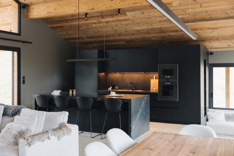 Cuisine noire en placage chêne et granit finition cuir dans un chalet de montagne