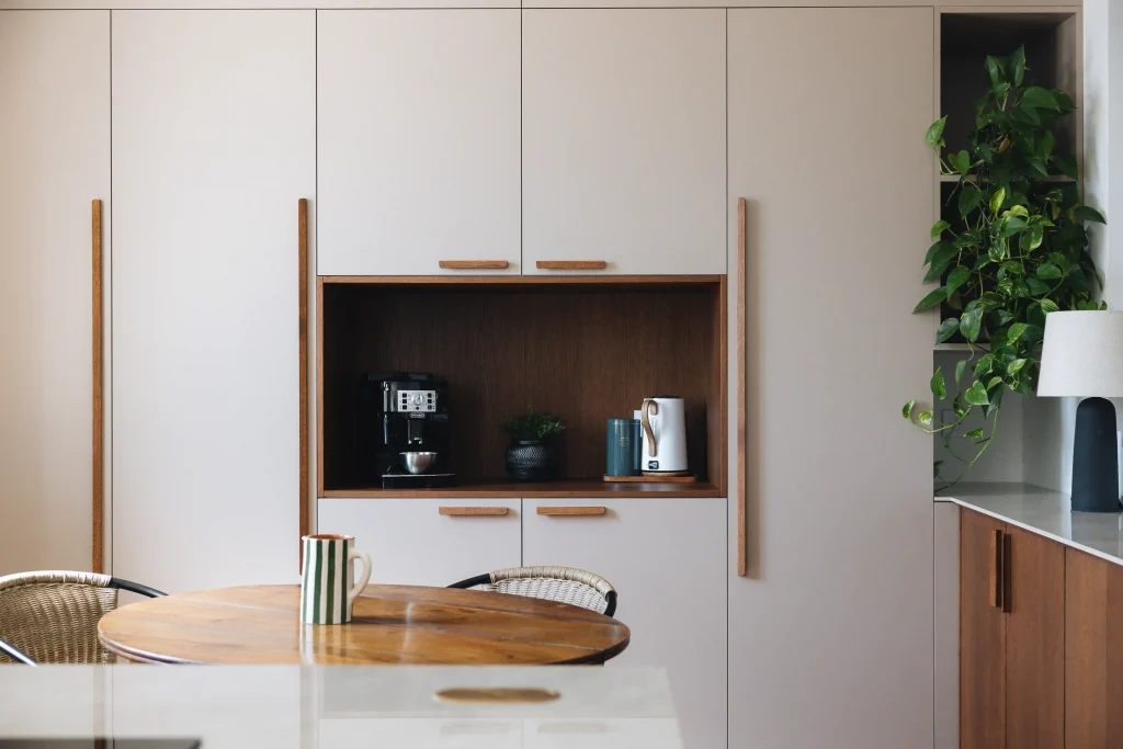 Cuisine bois Morel avec grand rangement toute hauteur beige, poignées bois et niche coin café en chêne teinté