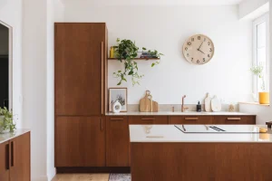 Cuisine en bois moderne Morel avec façades chêne teinté noyer, plan de travail clair et robinetterie cuivre