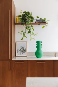cuisine en bois noyer foncé avec déco verte et plan de travail clair