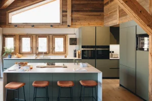cuisine vert olive dans un chalet avec plan de travail clair et poutres en bois