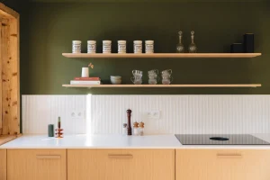 cuisine en bois clair avec mur vert sapin et étagères ouvertes