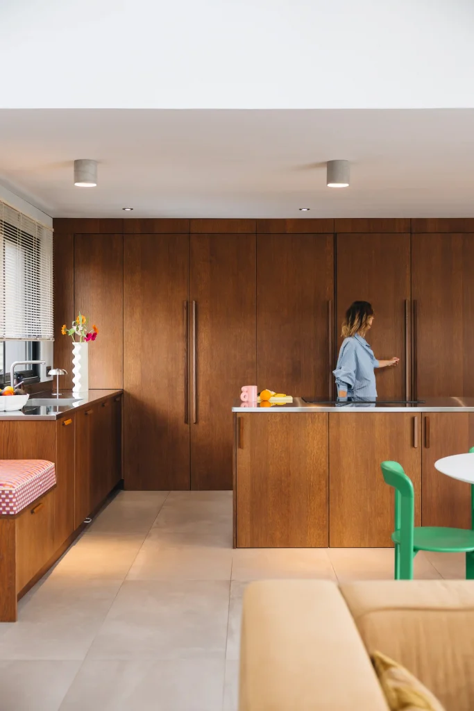 Cuisine bois moderne Morel en noyer avec grand mur de rangements toute hauteur, îlot central, banquette intégrée et touches colorées