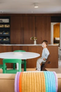 cuisine en bois noyer foncé avec table ronde blanche et chaises vertes