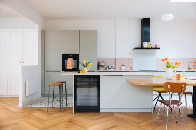 Cuisine colorée en façade sauge, crédence rose et table intégrée à l'îlot